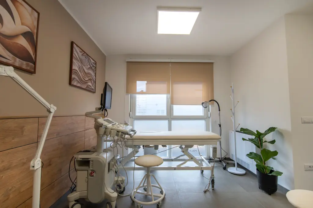 Heller Untersuchungsraum mit Liege, Lampe und Fenster